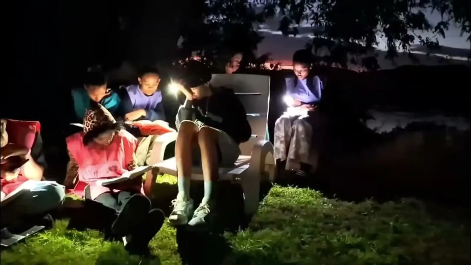 Campers reading their Bibles at night by torchlight