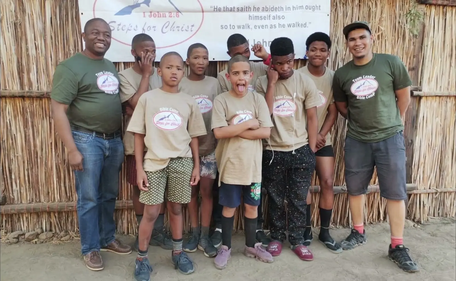 Two camp leaders with campers in front of a Steps for Christ banner