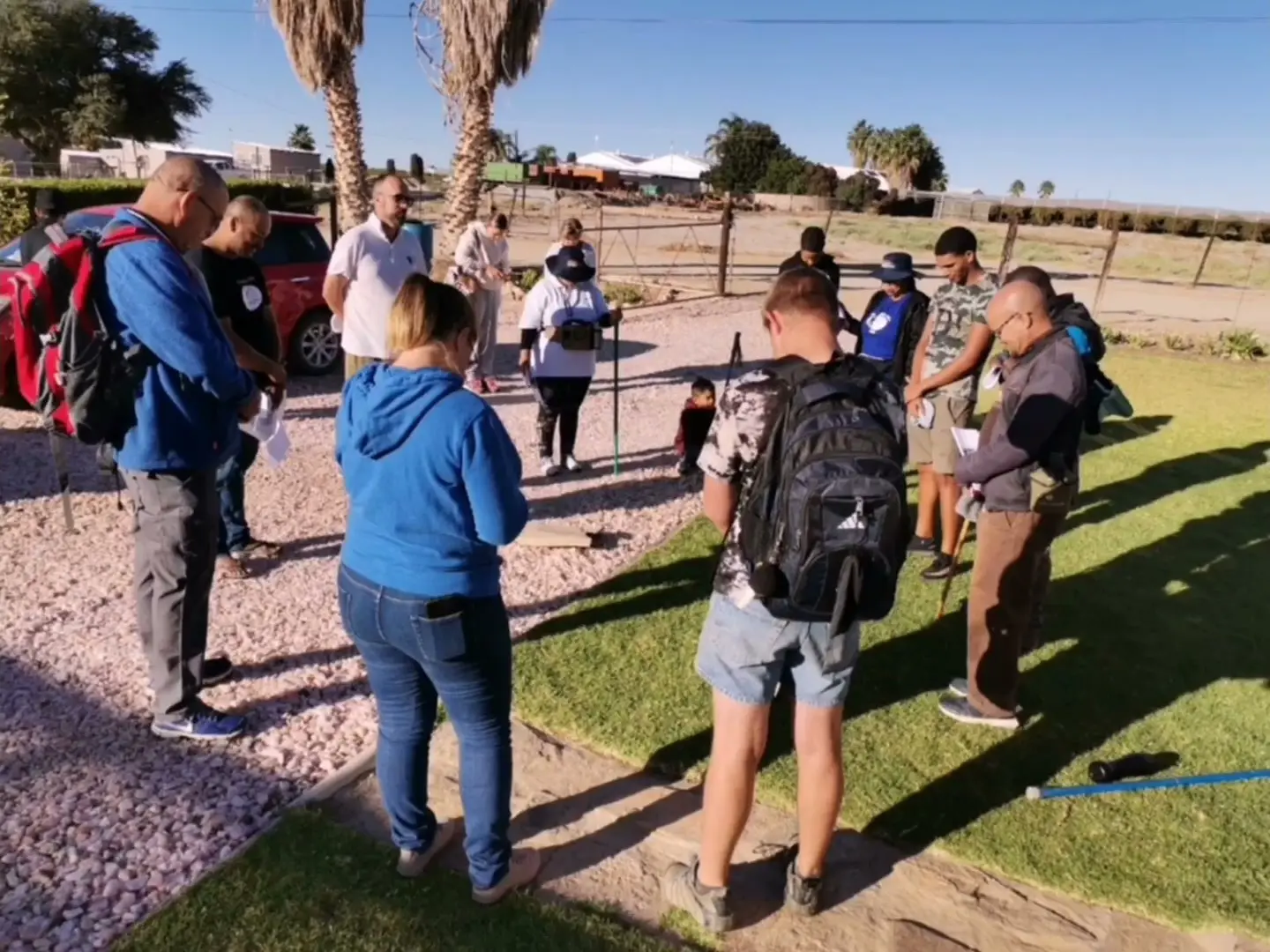 Hikers gathered in a circle beside a gravel path
