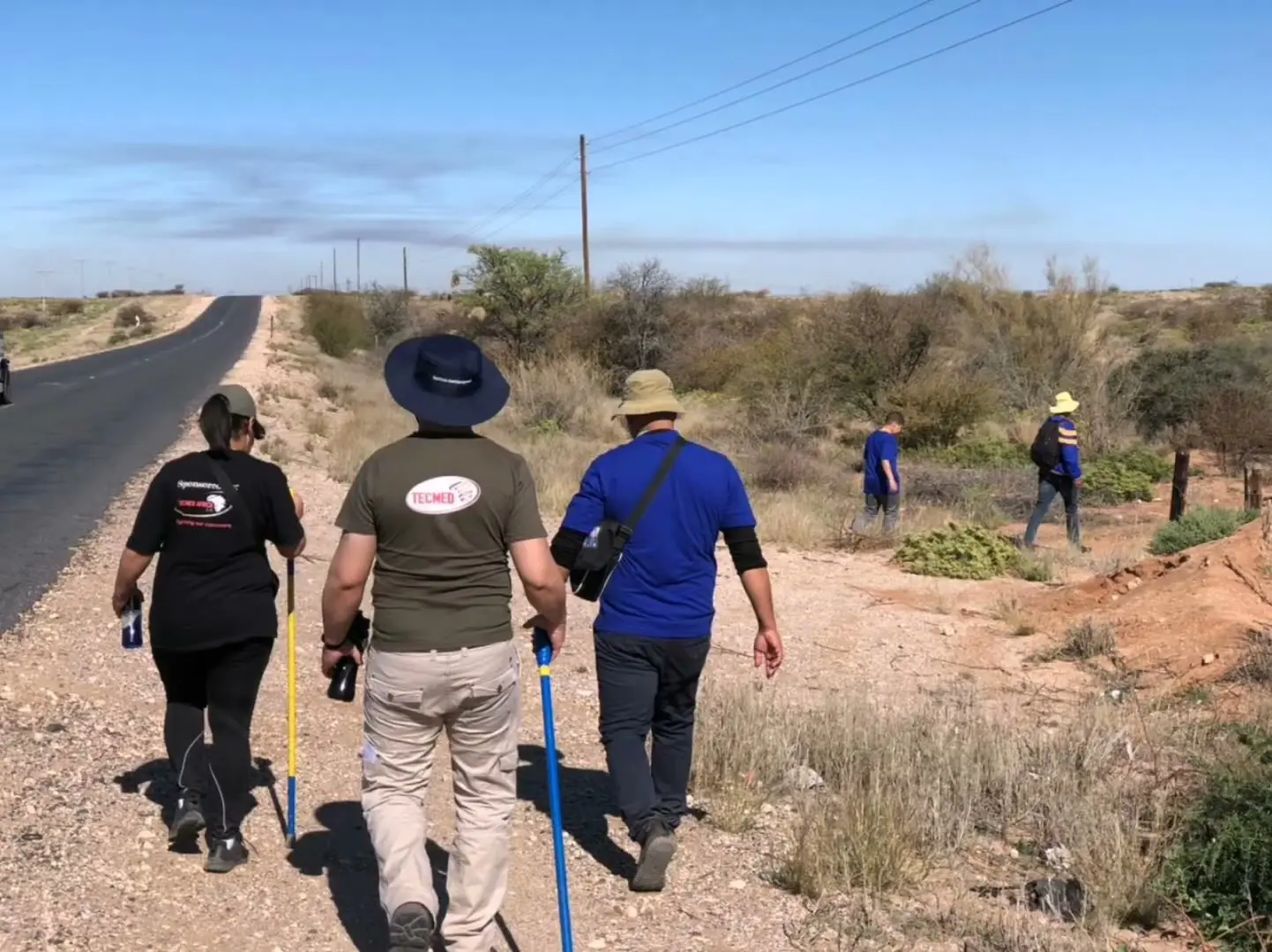 Hikers with walking sticks beside a road